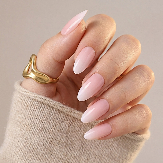 Pink ombre almond press-on nails with gradient finish on hand wearing gold ring