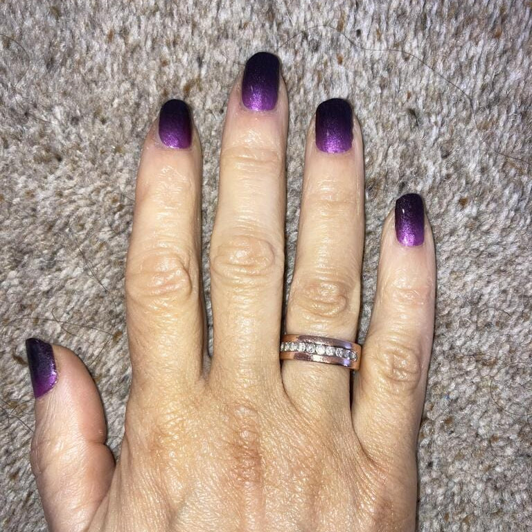 Purple black ombré gradient nail wraps on hand against grey textured background