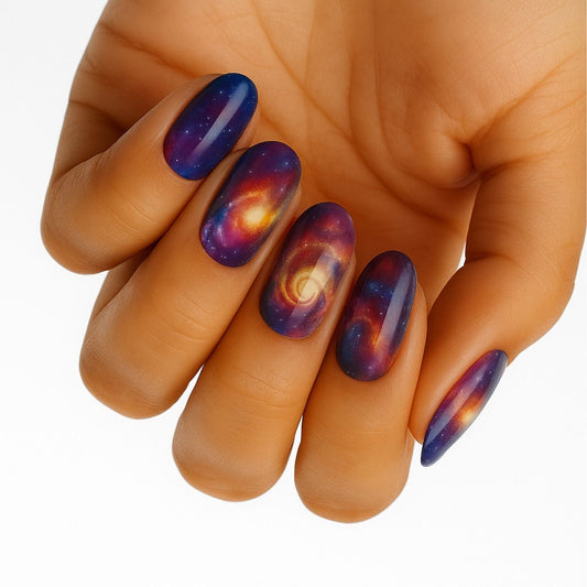 Galaxy space nail wraps on hand showing cosmic purple orange nebula patterns