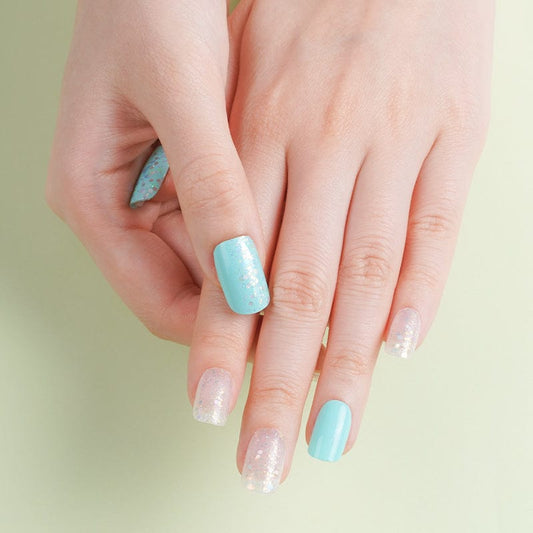 Turquoise and clear sparkly gel nail wraps on hand showing azure blue and glitter manicure