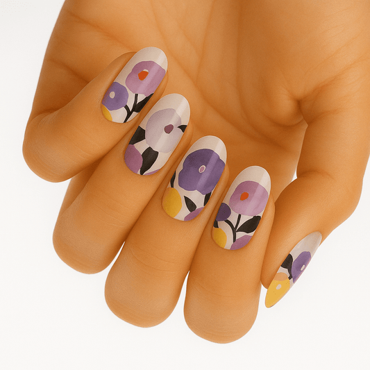 Purple and pink floral nail wraps on hand featuring botanical leaf patterns for spring manicure