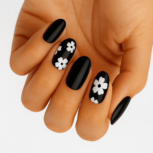 Black nail wraps with white daisy floral pattern on hand showing at-home manicure