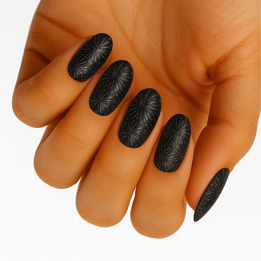 Black dandelion pattern nail wraps on hand showing dark botanical nail art design