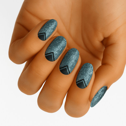 Blue geometric nail wraps on hand showing glittery textured pattern with silver accents