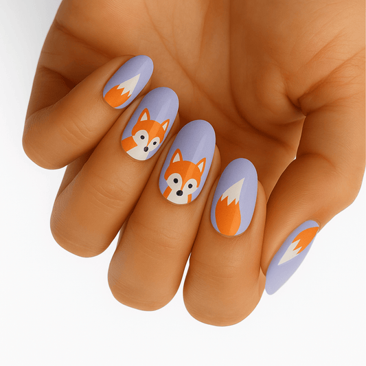 Cute fox nail wraps on hand featuring orange and grey cartoon foxes on lilac base