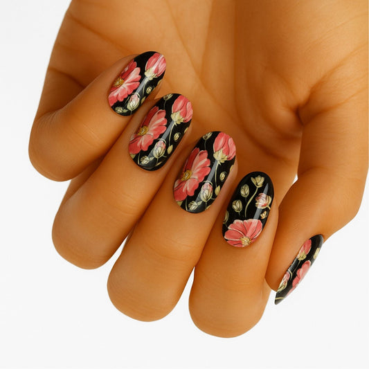 Black floral nail wraps on hand featuring pink hibiscus flowers with green leaves