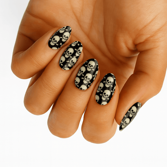 Black nail wraps with white skull pattern on hand showing gothic Halloween nail art