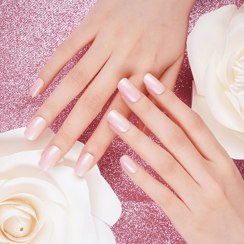 Hands wearing pink ombre nail wraps with white roses showing romantic manicure style