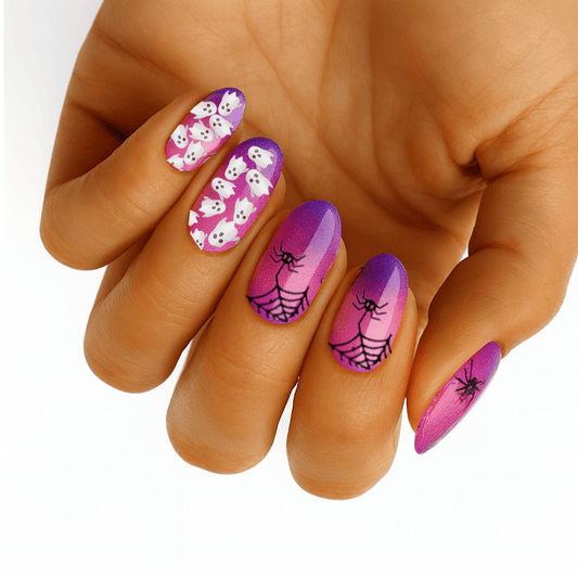 Pink and purple Halloween nail wraps with skulls and spiders on hand for spooky manicure