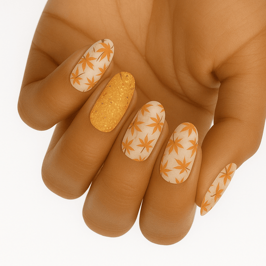 Orange and gold glitter nail wraps with white maple leaf pattern on hand