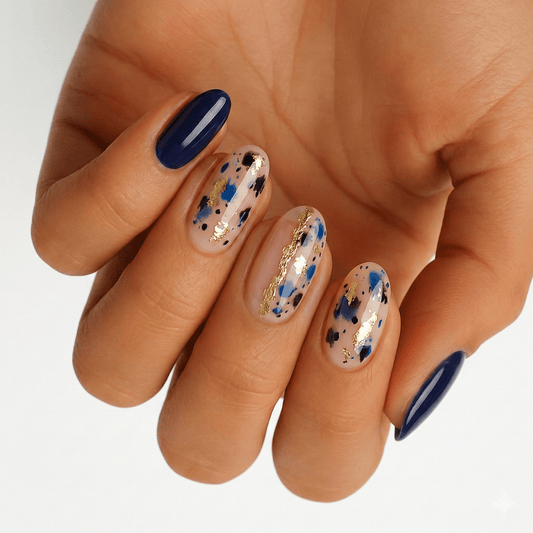 Navy blue and sheer terrazzo pattern nail wraps with gold foil accents on hand