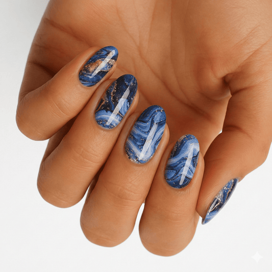 Blue marble nail wraps on hand with metallic copper veining and abstract stone patterns