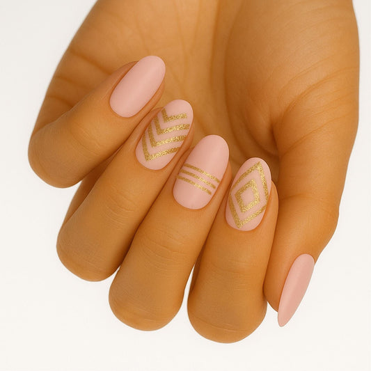 Pink gel nail wraps with gold geometric patterns on hand manicure