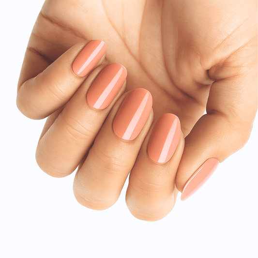 Glossy peach nail wraps on hand showing warm coral at-home manicure