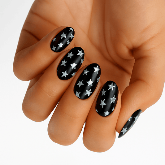 Black nail wraps with silver star pattern on hand showing celestial nail art