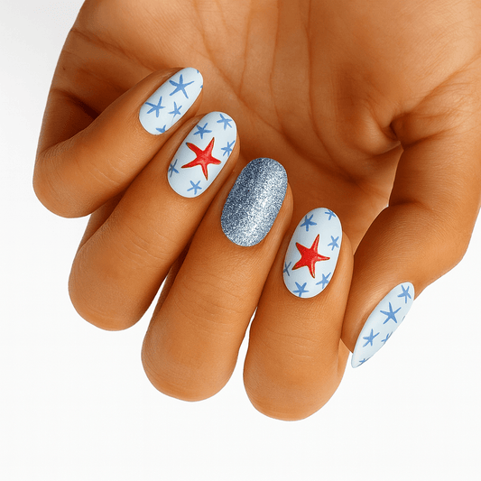 Hand showcasing white nail wraps with red and blue starfish patterns plus glitter accent nail