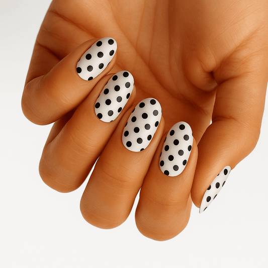 White nail wraps with black polka dots on hand showing retro pattern manicure