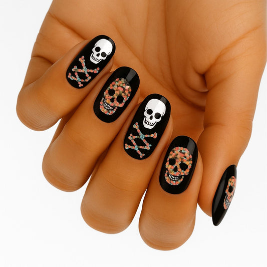 Halloween skull nail wraps on hand featuring black design with white sugar skull patterns
