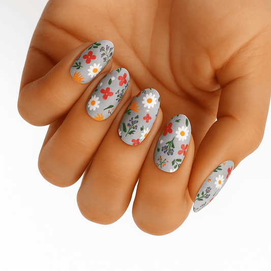 Hand displaying delicate white floral nail wraps with multicoloured wildflower whimsy pattern