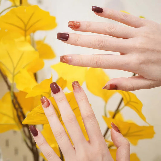Hands with autumn amber clouds gel nail wraps in brown and orange marble pattern
