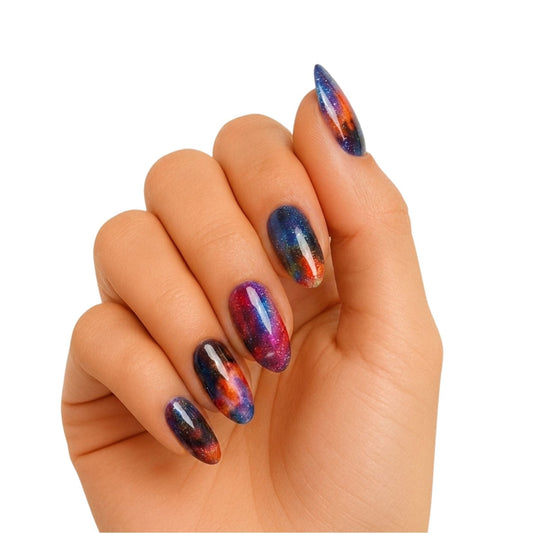 Cosmic galaxy gel nail wraps on hand showing iridescent purple blue chrome finish