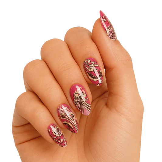 Pink rose gold gel nail wraps with ornate baroque swirl patterns on hand