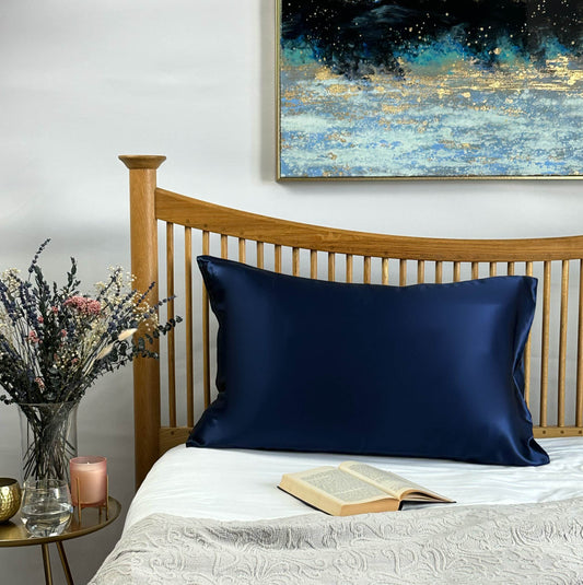 Navy blue silk pillowcase on wooden bed frame for premium sleep comfort