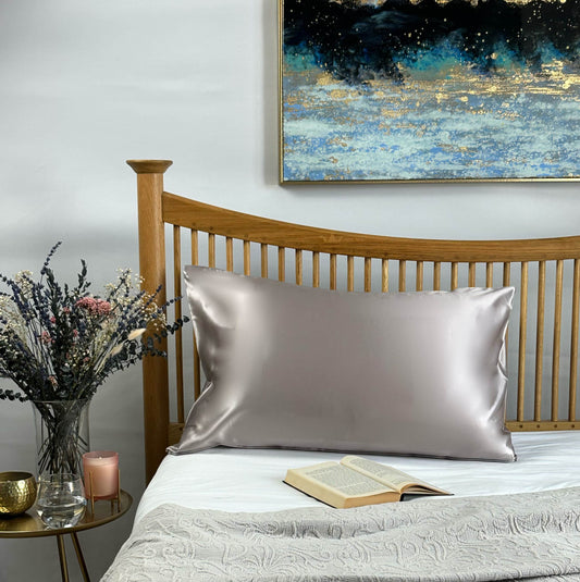 Taro grey silk pillowcase on wooden bed frame with artwork and dried flowers