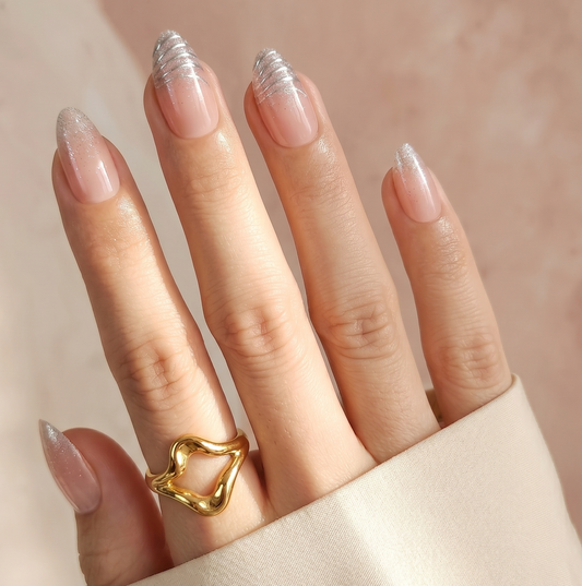 Sheer nude press-on nails with silver glitter French tips, almond shape.