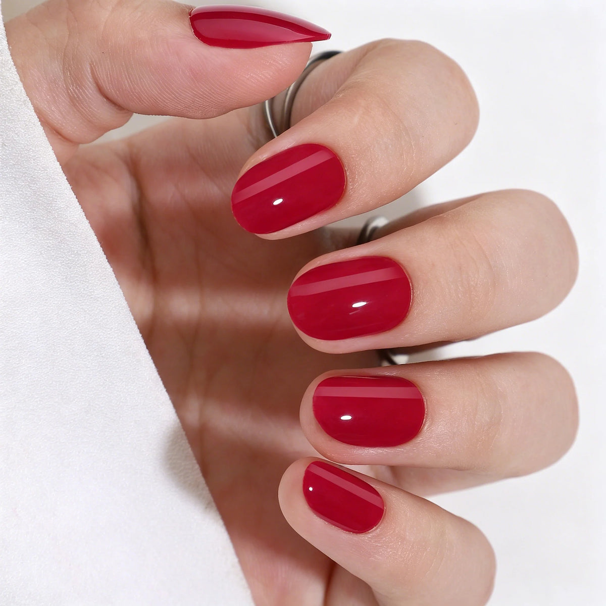 Short oval soft gel press-on nails in glossy cherry red, solid high-shine finish