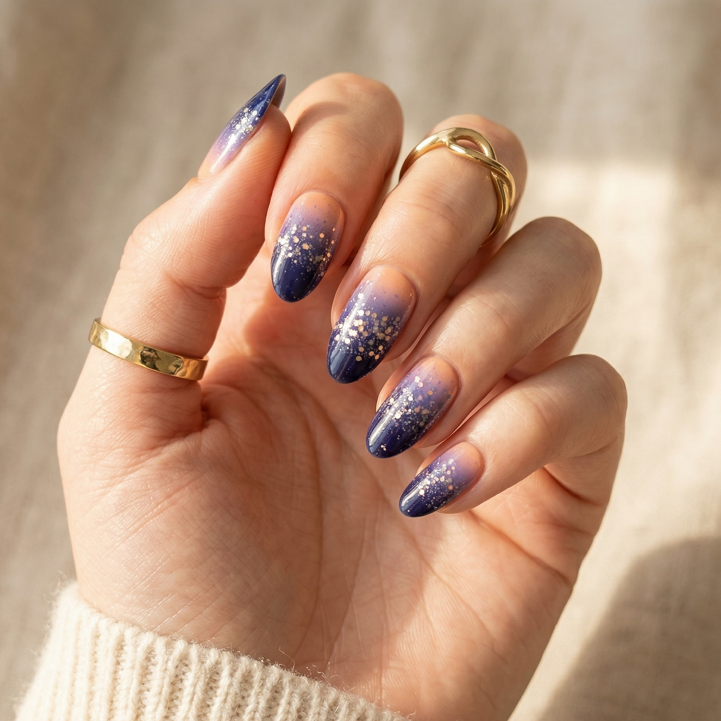Navy blue ombre gel nail wraps with glitter gradient on hand wearing gold rings