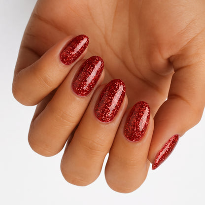 Glossy red glitter nail wraps on almond-shaped nails, sparkling crimson finish
