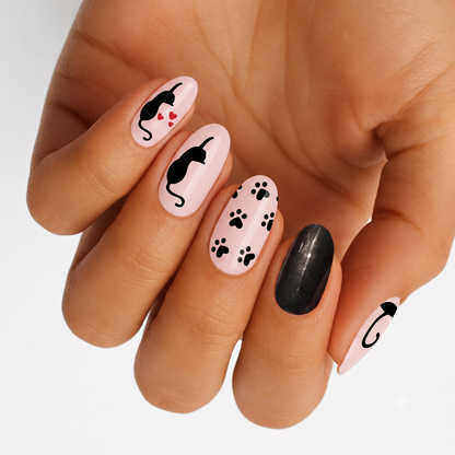 Pink nail wraps with black cat silhouettes, paw prints, hearts, and black glitter accent nail.