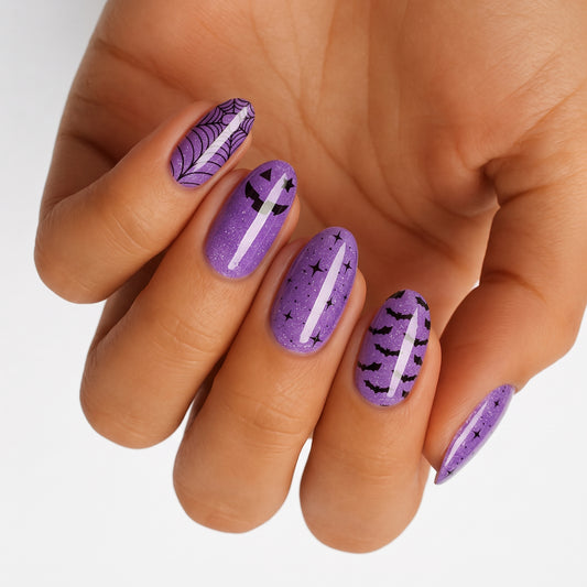 Purple glitter semi-cured gel nail wraps with Halloween spiderweb, pumpkin, bat, and star designs