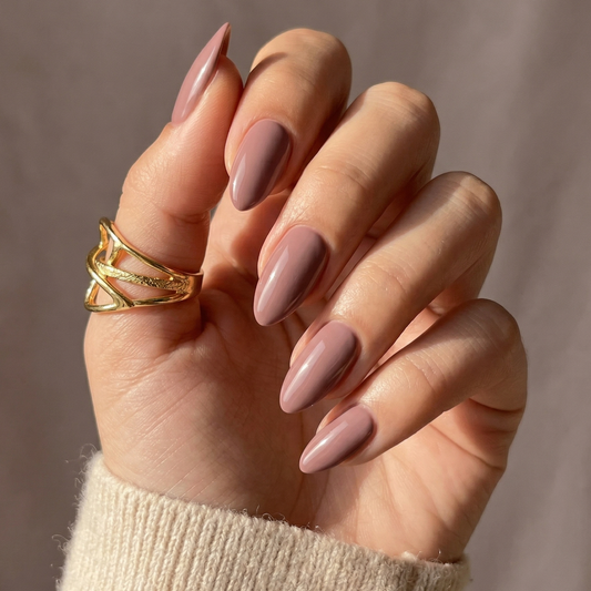 Dusty pink soft gel press-on nails in short almond shape on hand with gold ring