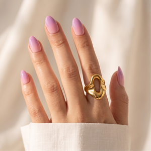 Glossy lilac purple semi-cured gel nail wraps on almond-shaped nails, gold ring accent