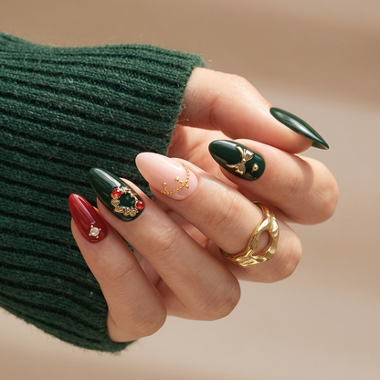 Glossy dark green and red press-on nails with gold bow, chain, and gem charms