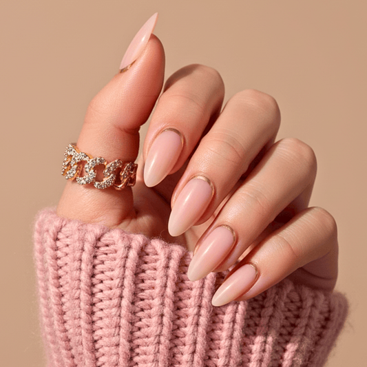 Nude pink glazed press-on nails in short almond shape on hand with pink jumper