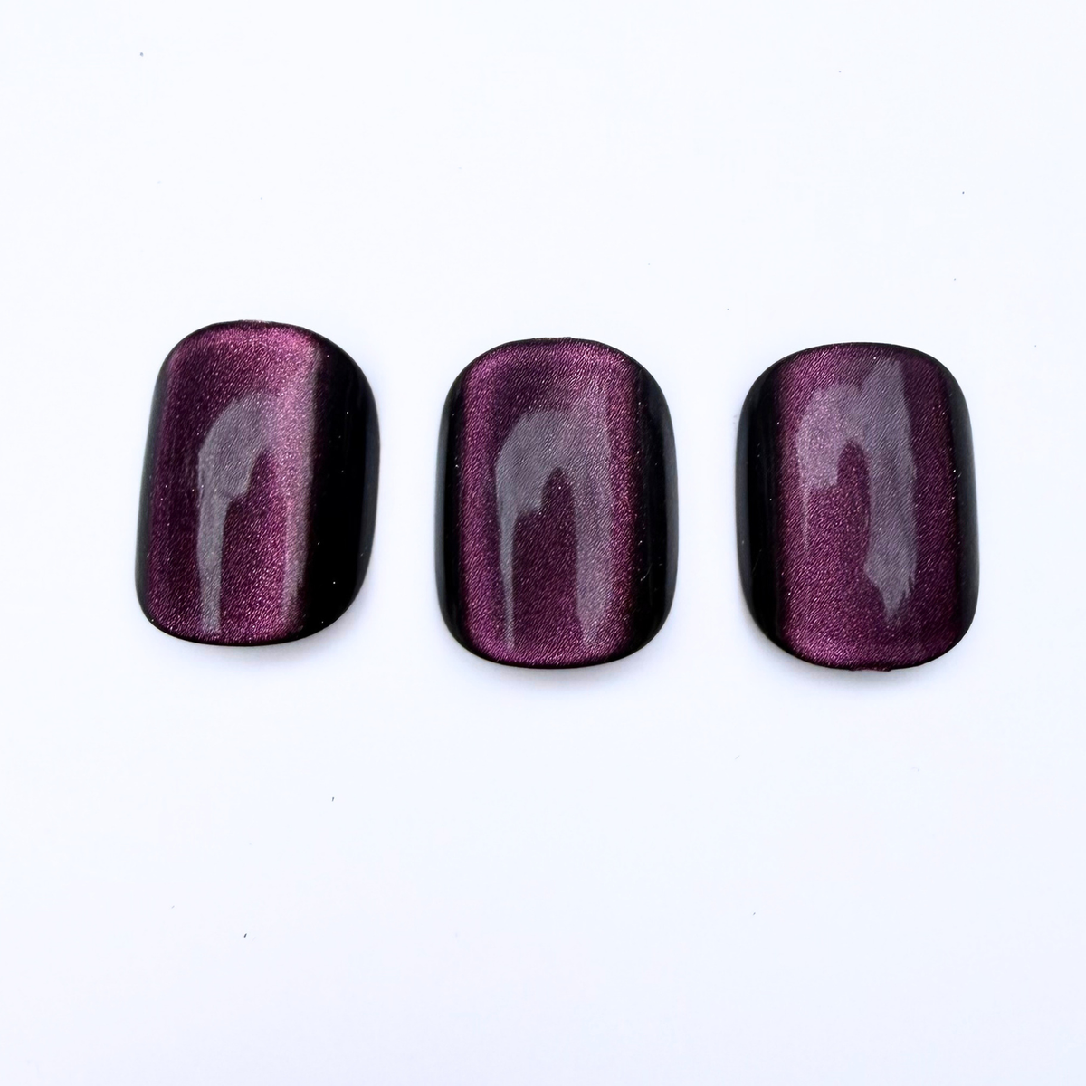 Deep plum cat-eye press-on nails with black edges and magnetic shimmer stripe