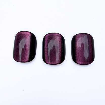 Deep plum cat-eye press-on nails with black edges and magnetic shimmer stripe