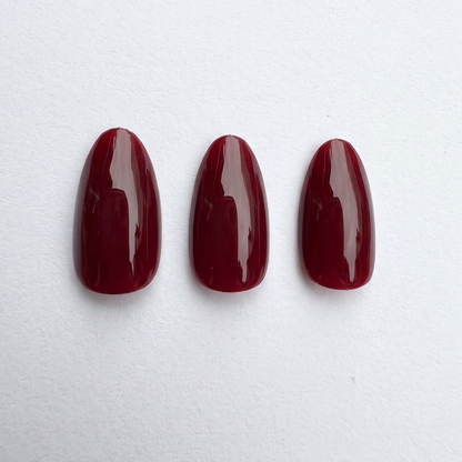 Deep dark red glossy press-on nails, almond shape, solid color finish