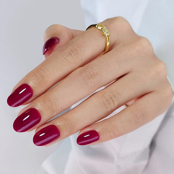Short oval soft gel press-ons in glossy deep berry-red, solid colour finish