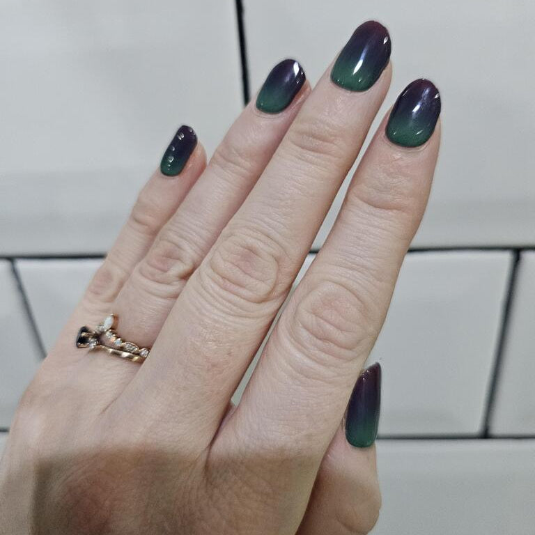 Green burgundy gradient gel nails on hand with gold chain ring accessory