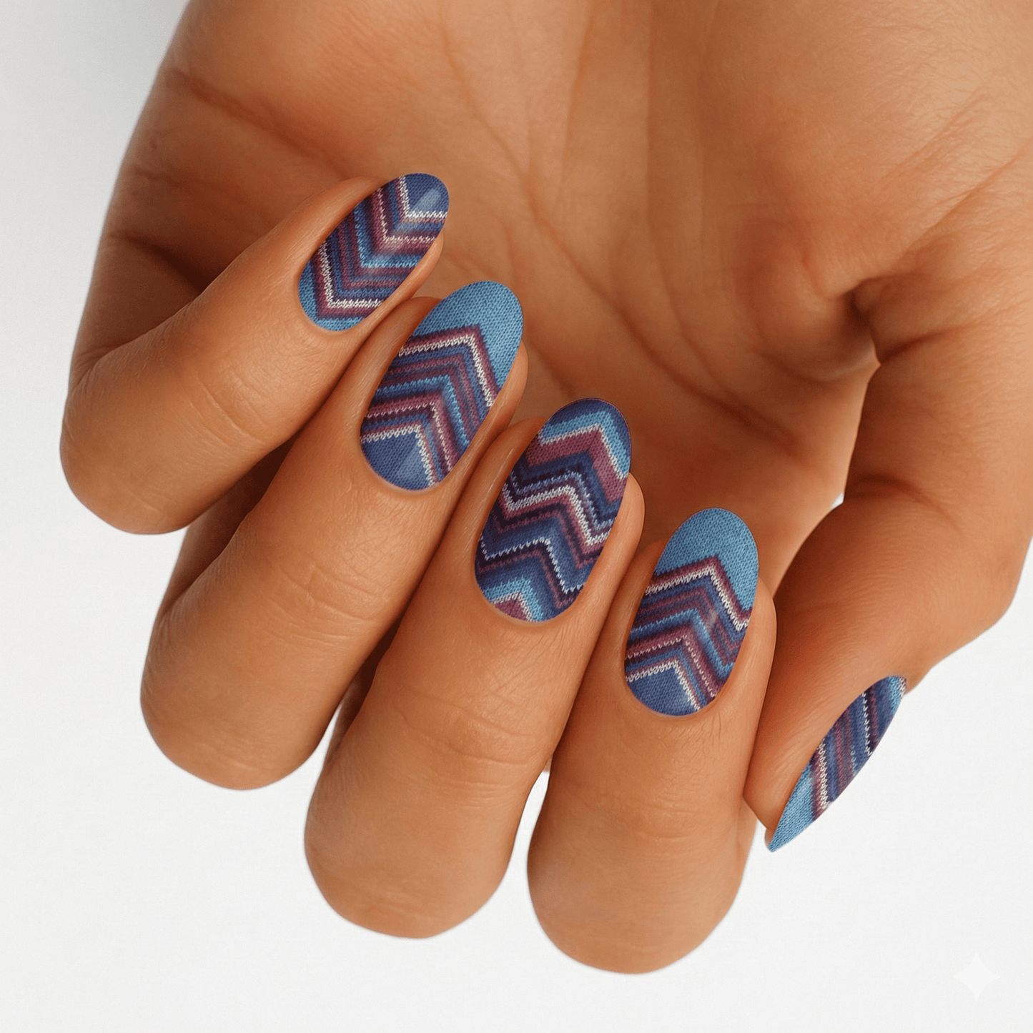 Hand wearing blue chevron pattern nail wraps in geometric design