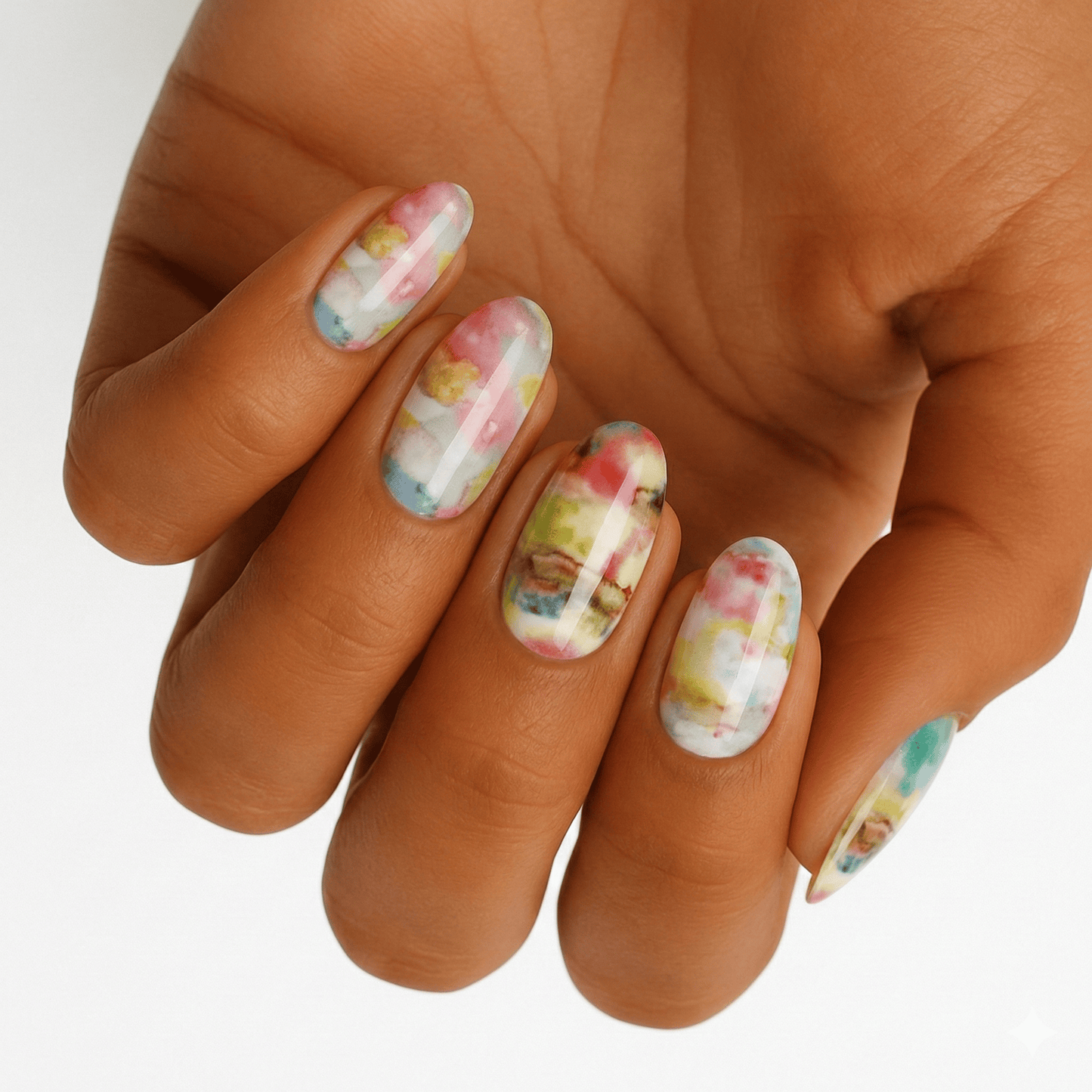Hand wearing pastel watercolour nail wraps with abstract dreamy design in pink and green