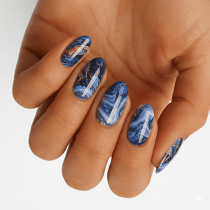 Blue marble nail wraps on hand with metallic copper veining and abstract stone patterns