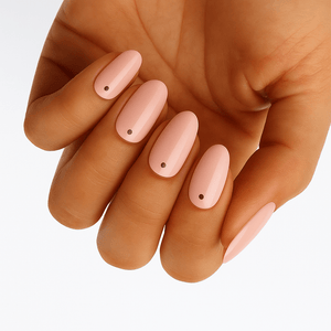 Nude pink nail wraps with black polka dots on hand showing minimalist spot manicure