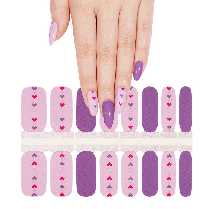 Hand showing pink and purple heart nail wraps sheet for at-home manicure
