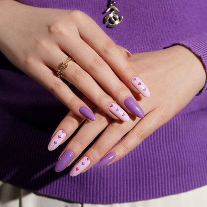 Purple jumper styled hands showing pink heart pattern nail wraps for Valentine's Day manicure