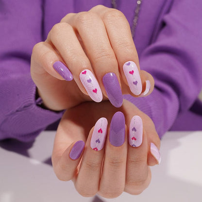 Hands displaying purple gel nail wraps with pink hearts in cute Valentine's Day nail art
